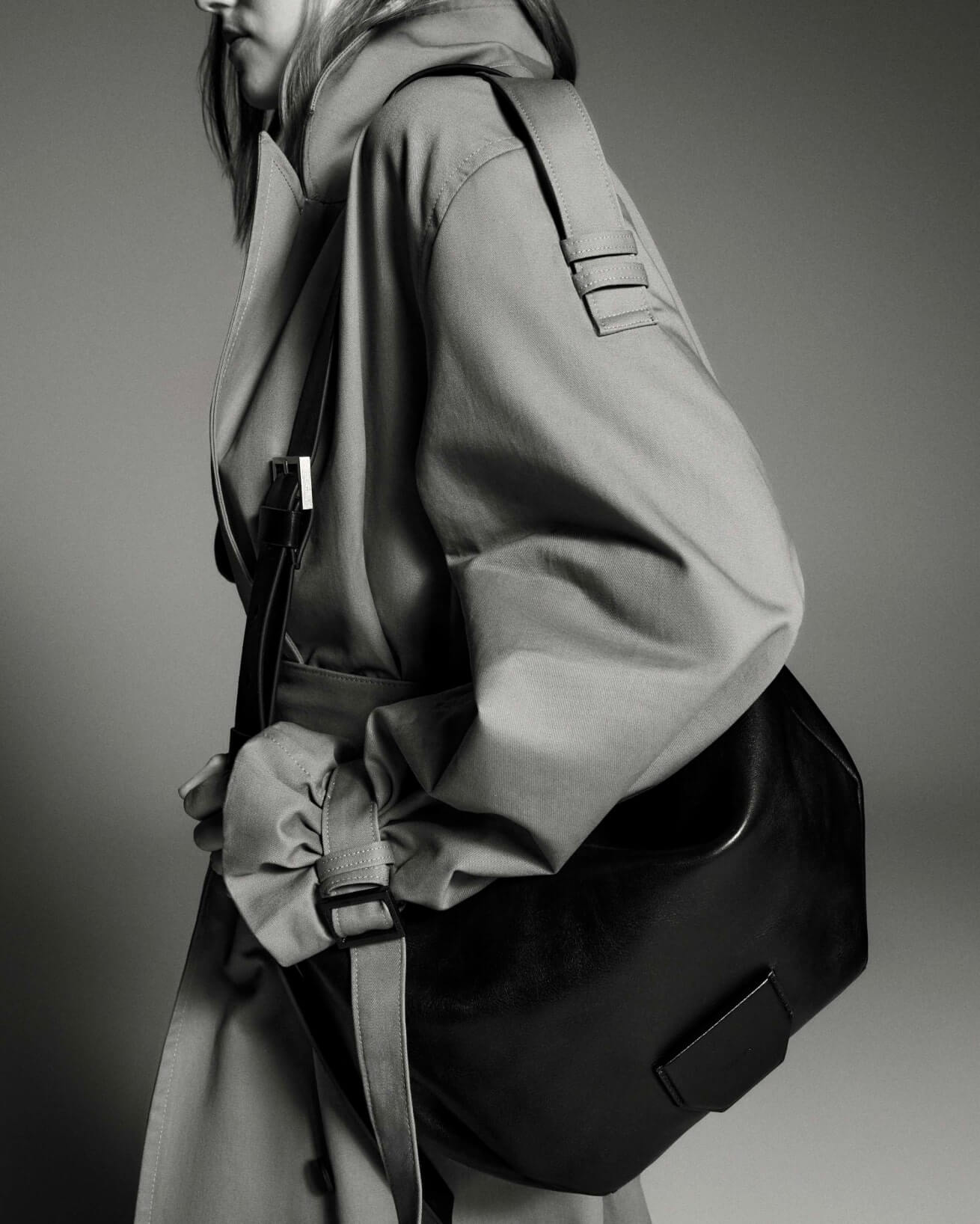 Woman wearing a white shirt, with suede leather shoulder bag and statement earrings and bracelet.